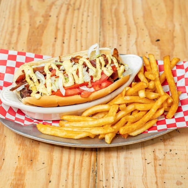 A Jumby Bay Island Grill sandwich with bacon, lettuce, tomato, onions, and mustard, served with fries.
