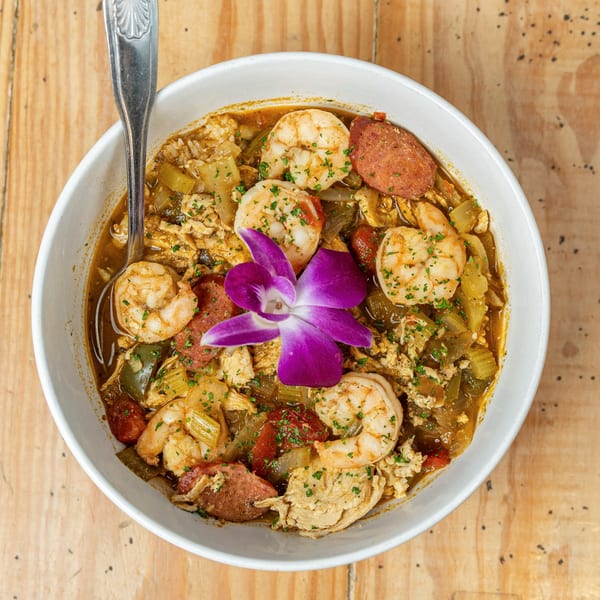 Jumby Bay Island Grill's seafood gumbo with shrimp, sausage, and vegetables, garnished with a purple orchid.